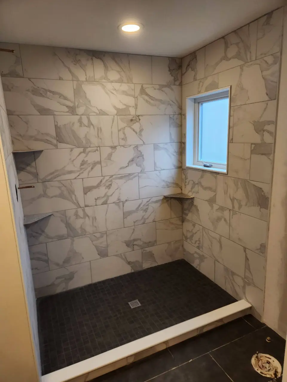 Walk-in shower with marble-look tile and a dark floor