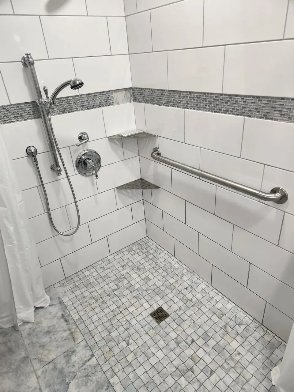 Shower with grab bars, handheld sprayer and mosaic floor