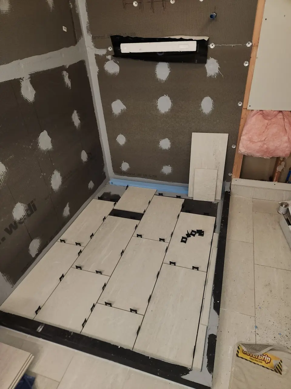 Shower floor tile being laid over waterproofing